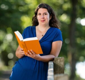 Katrin Opatz lehnt sich an ein Geländer mit einem Buch in der Hand