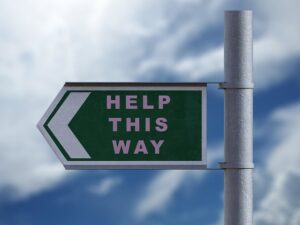 Schild mit der Aufschrift "Help this way": Die Aufgabe einer Lektorin ist, Hilfe für Autor*innen zu leisten