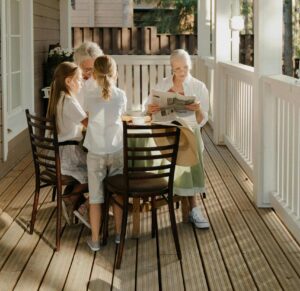 Gorßeltern sitzen mit ihren Enkeltöchtern auf einer Veranda